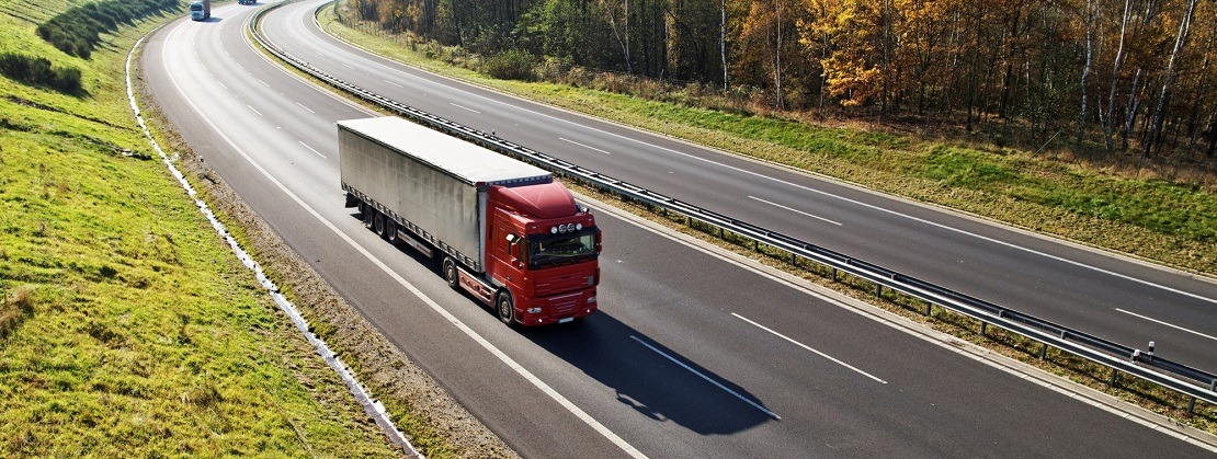 The highway between deciduous forests with leaves in fall colors, the highway ride three trucks