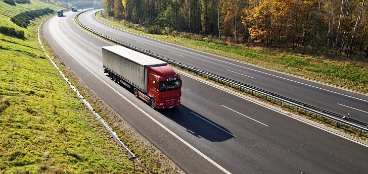 The highway between deciduous forests with leaves in fall colors, the highway ride three trucks