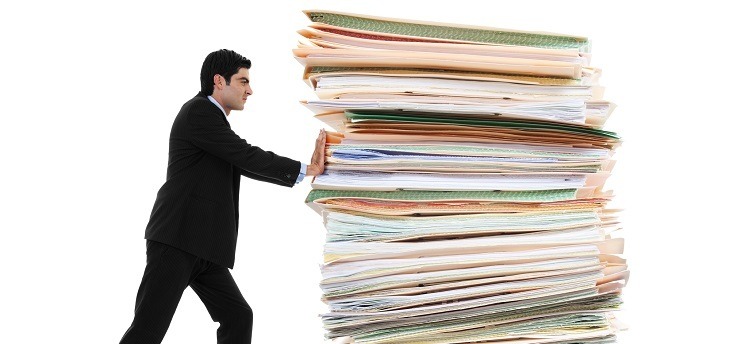 Stock image of businessman pushing a giant stack of documents isolated on white background