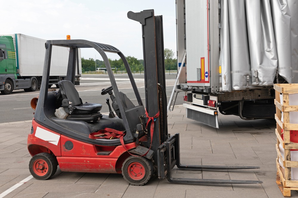 Gas powered forklift next to a truck outside