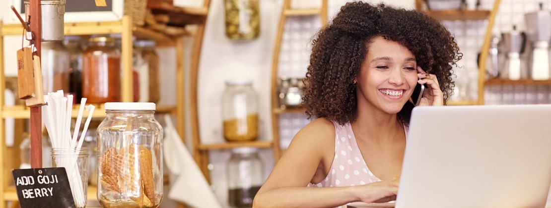 A small business owner smiling while working and on the phone