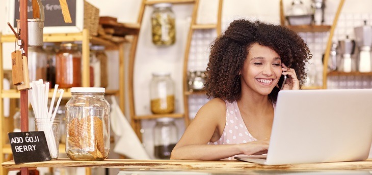 A small business owner smiling while working and on the phone