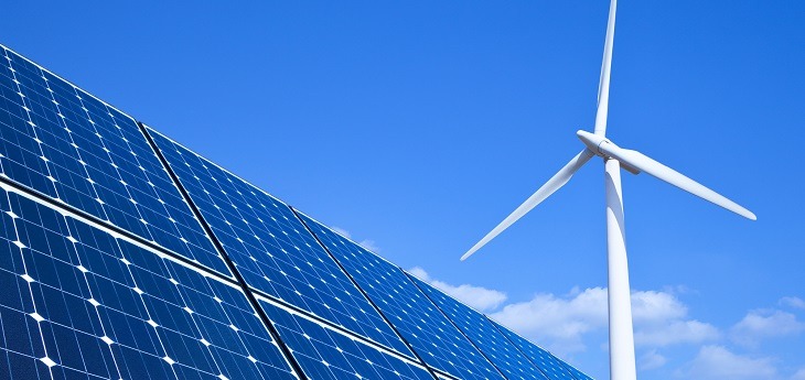 Solar panels and wind turbine against blue sky