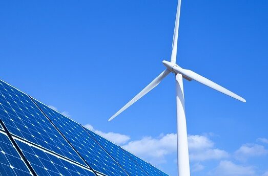 Solar panels and wind turbine against blue sky