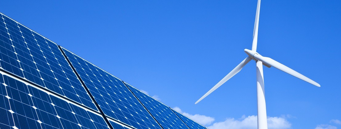 Solar panels and wind turbine against blue sky