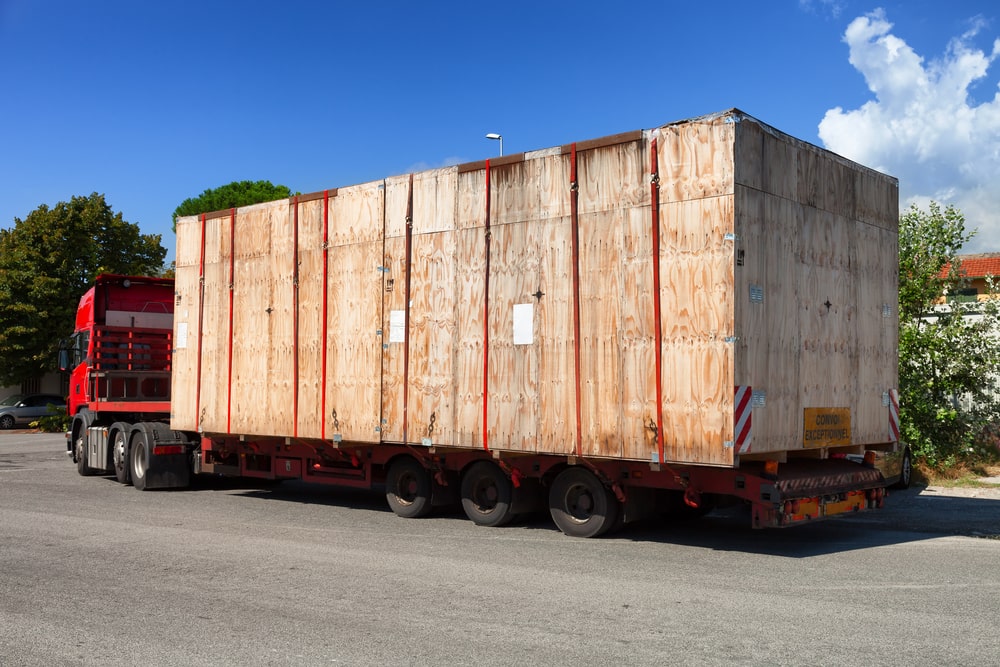 A red truck hauling oversized cargo in a crate
