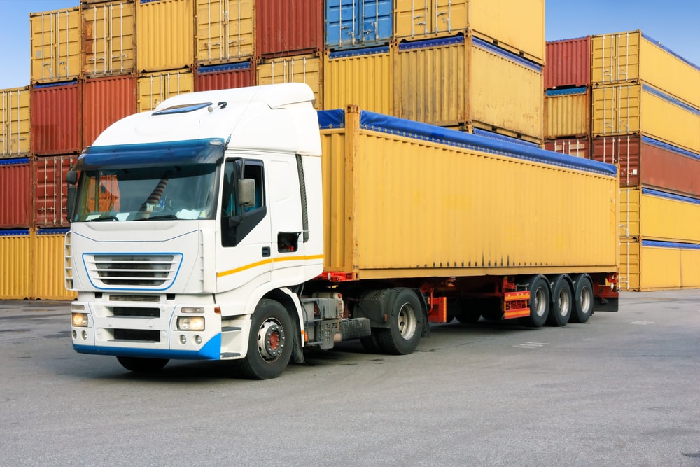 A truck loaded with a yellow container at a port