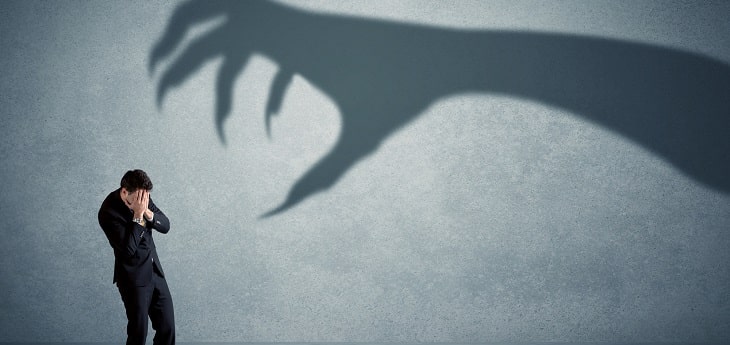 A businessman afraid of a hand shaped shadow