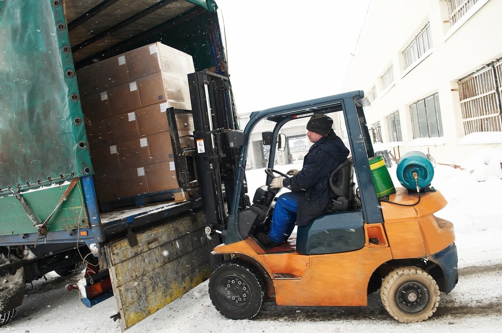 Forklift operator working by a freight truck