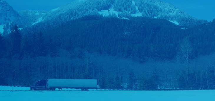 A freight truck moving by a mountainside