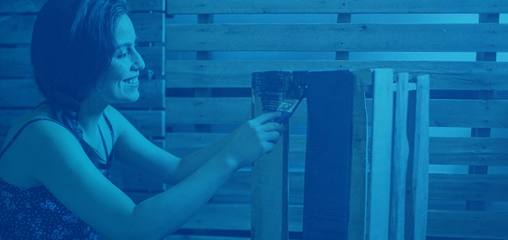 A woman painting a pallet in black paint