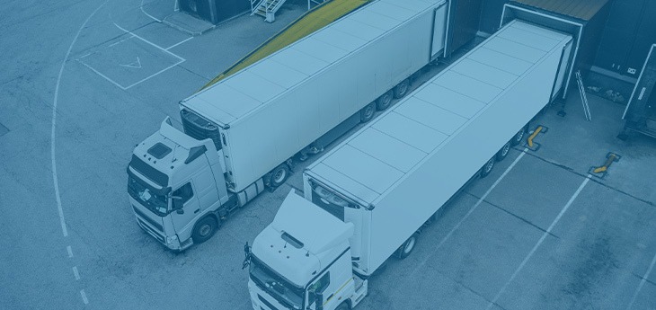 Two freight trucks parked at a loading dock