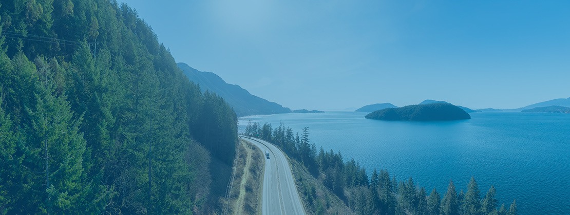 A truck traveling by road between the sea and a hillside