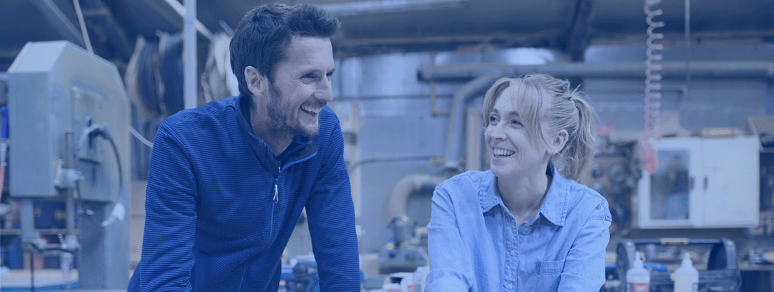 Two employees laughing by a laptop