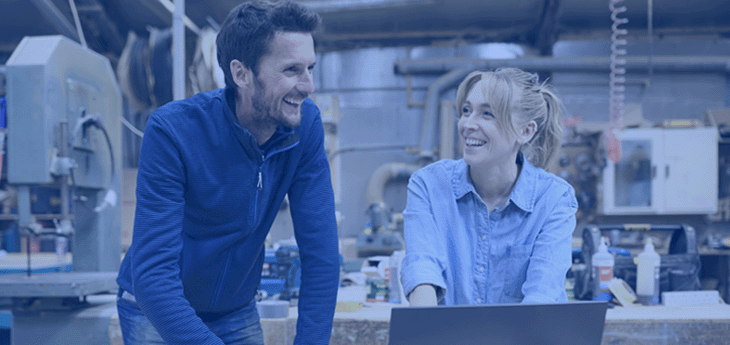 Two employees laughing by a laptop