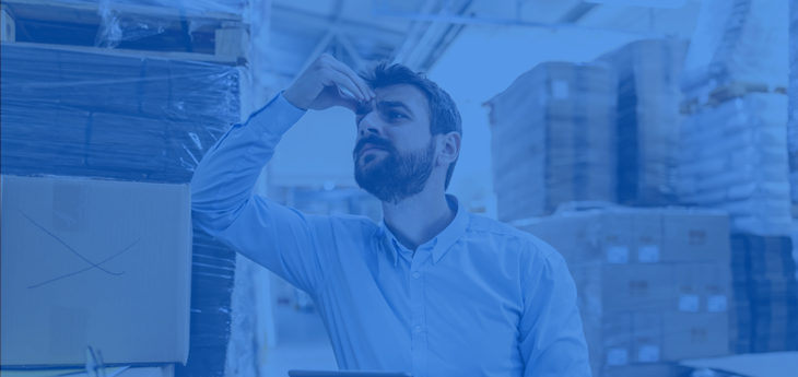 Man in warehouse holding his forehead