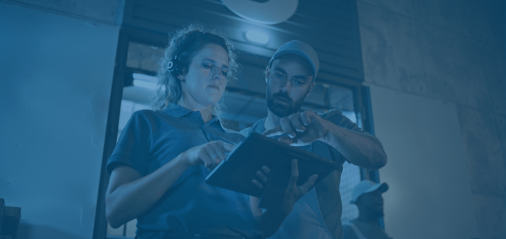 Male and female warehouse workers looking at data on a tablet.